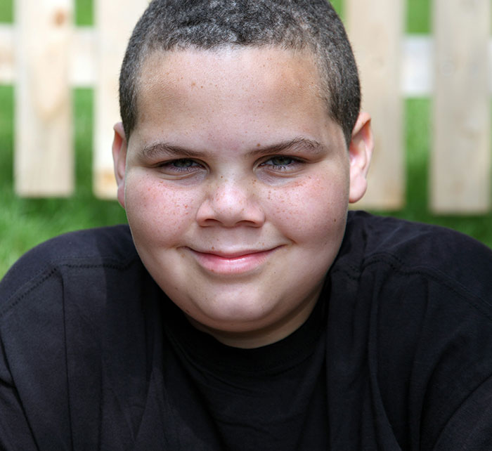 Smiling kid in school outdoors with a confident expression representing stories of kids who earned the weirdo title.