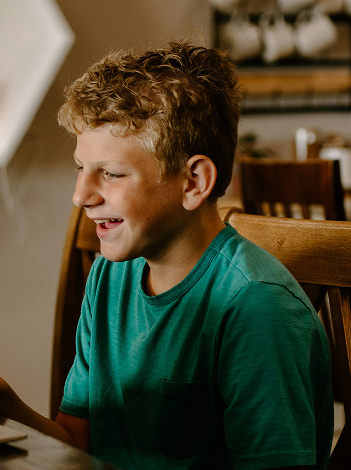 Young boy smiling indoors, representing kids in school who earned the weirdo title in a casual setting.
