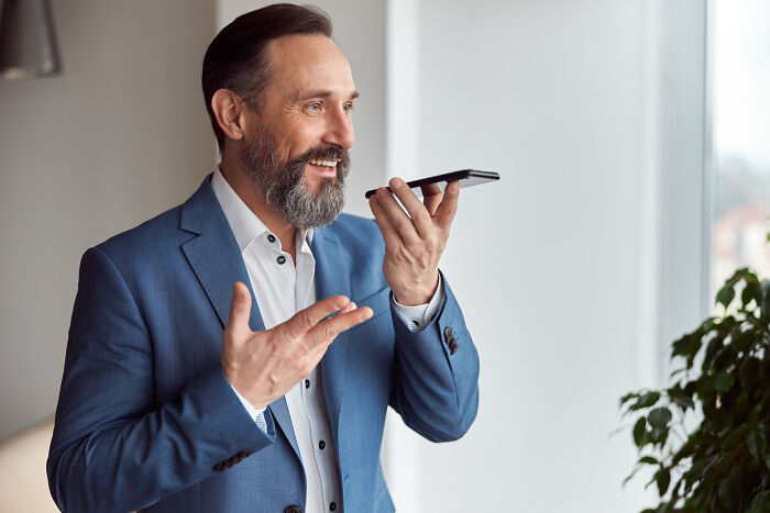 Man in blue suit speaking into smartphone, representing infidelity stories getting exposed through accidental texts.