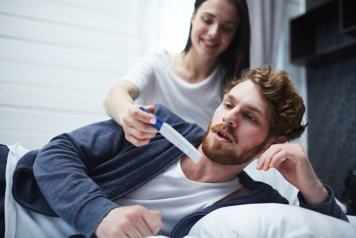 Couple in a bedroom with woman showing man a pregnancy test, illustrating themes of infidelity getting exposed.