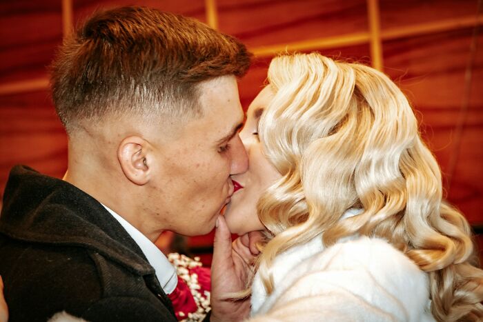Couple sharing a kiss at a wedding with a warm embrace, illustrating trashy wedding moments and tacky romance.