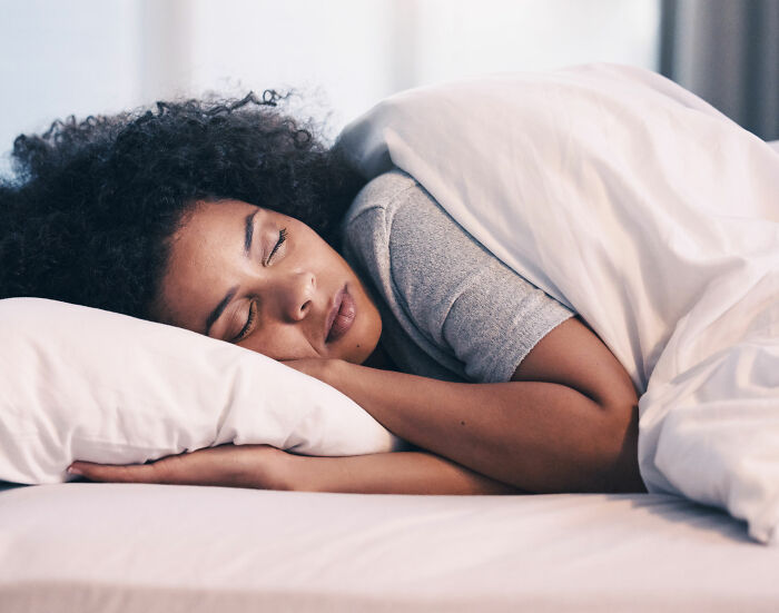 Woman peacefully sleeping in bed, highlighting the impact of crimes against wives discussed on depraved website.