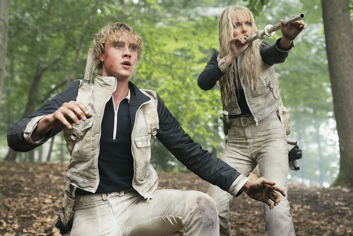 Two characters in a forest scene from the new The Hunger Games trailer recreating an iconic moment, fans excited.