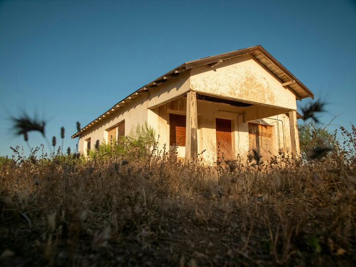 Abandoned and rundown building surrounded by dry weeds, representing one of the worst places in the US to visit.