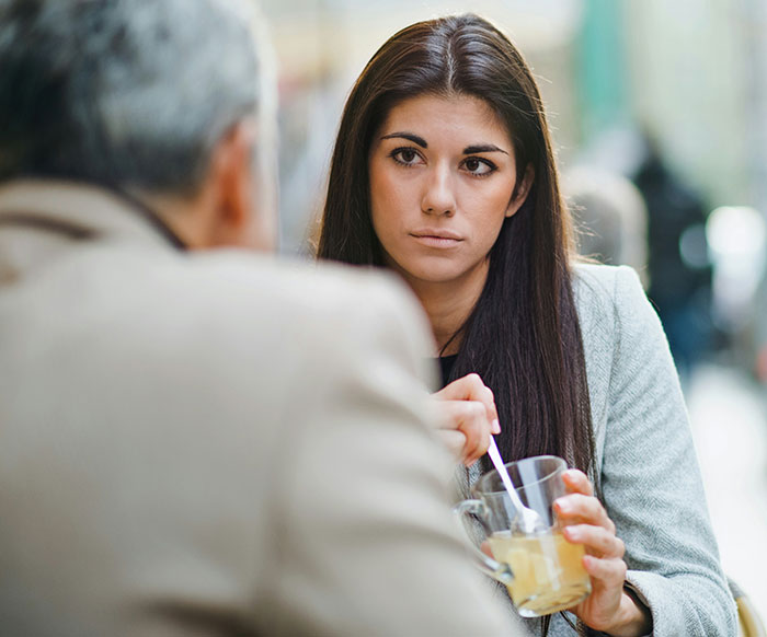 Young woman showing subtle displays of intelligence while having a thoughtful conversation over a drink.