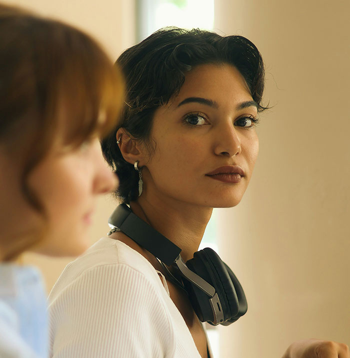 Young woman with headphones around her neck looking thoughtful, illustrating subtle displays of intelligence.