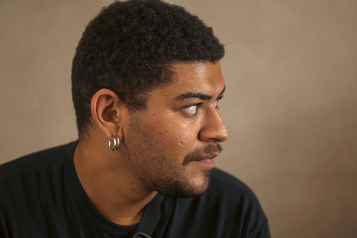 Young man with hoop earrings looking to the side, illustrating subtle and interesting displays of intelligence in a thoughtful pose.