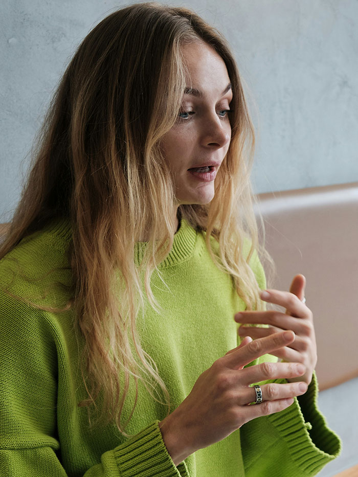 Young woman in green sweater using hand gestures while explaining subtle and interesting displays of intelligence.