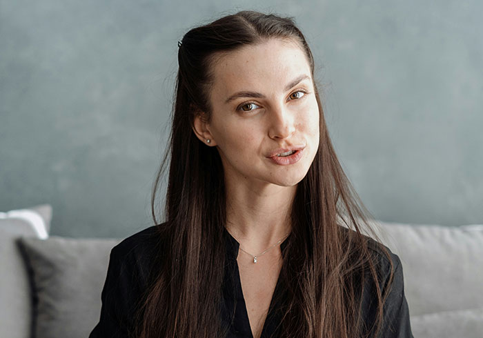 Young woman with long dark hair and thoughtful expression showing subtle displays of intelligence indoors