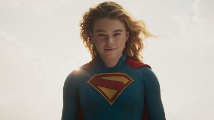 Supergirl star Milly Alcock in costume, standing confidently with sunlight behind her, preparing for backlash.