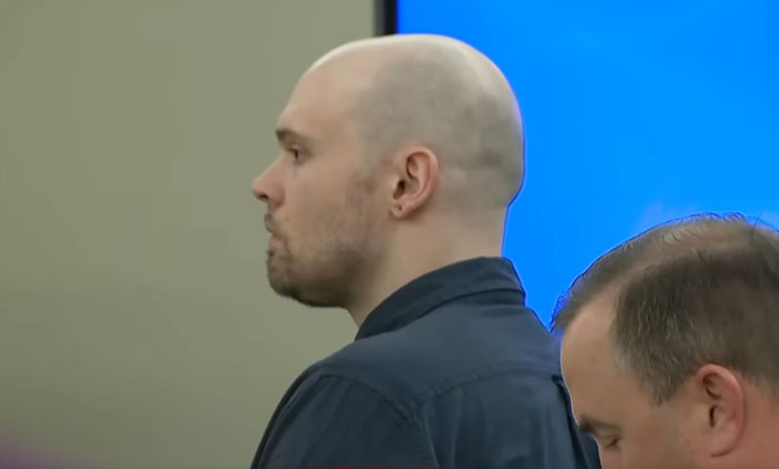 Man in a courtroom standing with serious expression, related to Athena Strand&rsquo;s mom confronting FedEx driver case.