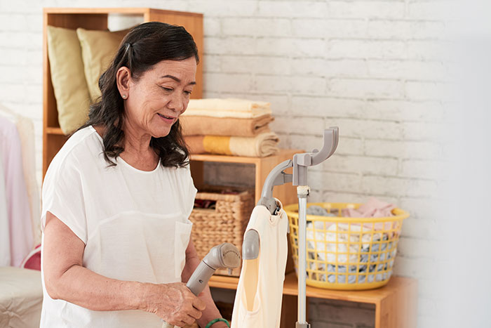 Wealthy mom holding a steamer in a laundry room, highlighting house help treated like family but living in a shed.