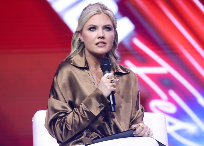Erika Kirk falando em um evento do ensino médio enquanto adolescentes expressam revolta por sua polêmica visita ao palco.