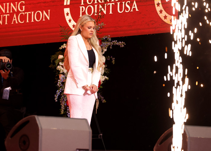 Erika Kirk falando em um evento da Turning Point USA durante uma polêmica visita a uma escola secundária em meio à revolta de adolescentes.