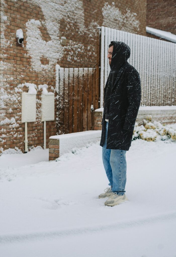 Man standing in heavy snow wearing a black coat and jeans, illustrating unexpected and bizarre ways people passed away.