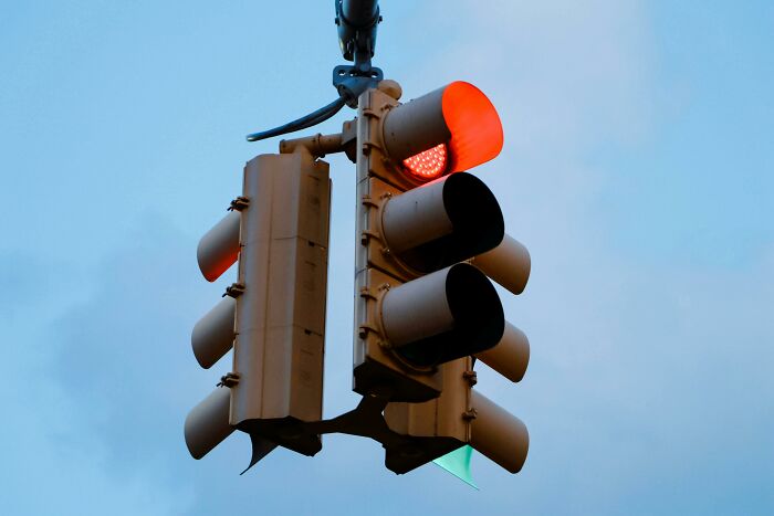Traffic light showing red signal against a clear sky symbolizing danger and being late with dark consequences.