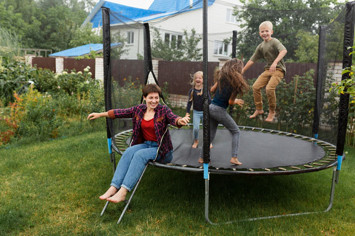 Family enjoying trampoline in backyard as HOA demands removal, highlighting dad's fight against HOA board rules.