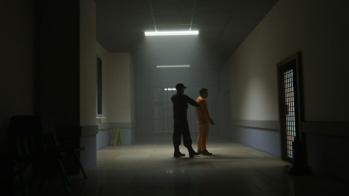 A person in an orange outfit escorted by a guard in a dimly lit hallway, highlighting the impact of horrible bullies.
