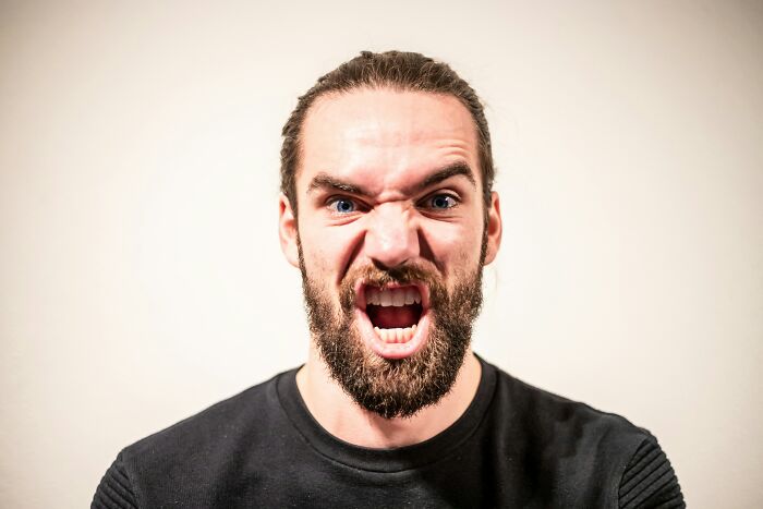 A man with a beard and ponytail, yelling in frustration with wide blue eyes, symbolizing people who rage quit their jobs.