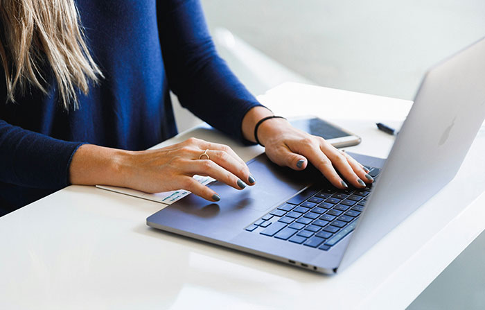 Person typing on a laptop, creatively using technology to succeed and get a job in a professional setting.