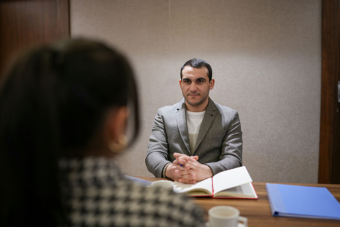 Man in gray blazer sitting at desk during a creative job interview with woman in a checkered shirt, showcasing job success.