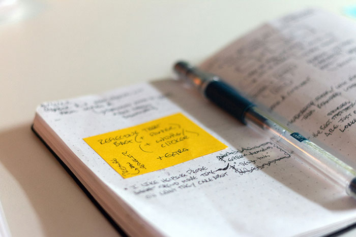 Open notebook with handwritten notes and a pen, illustrating creative job application ideas and strategies.