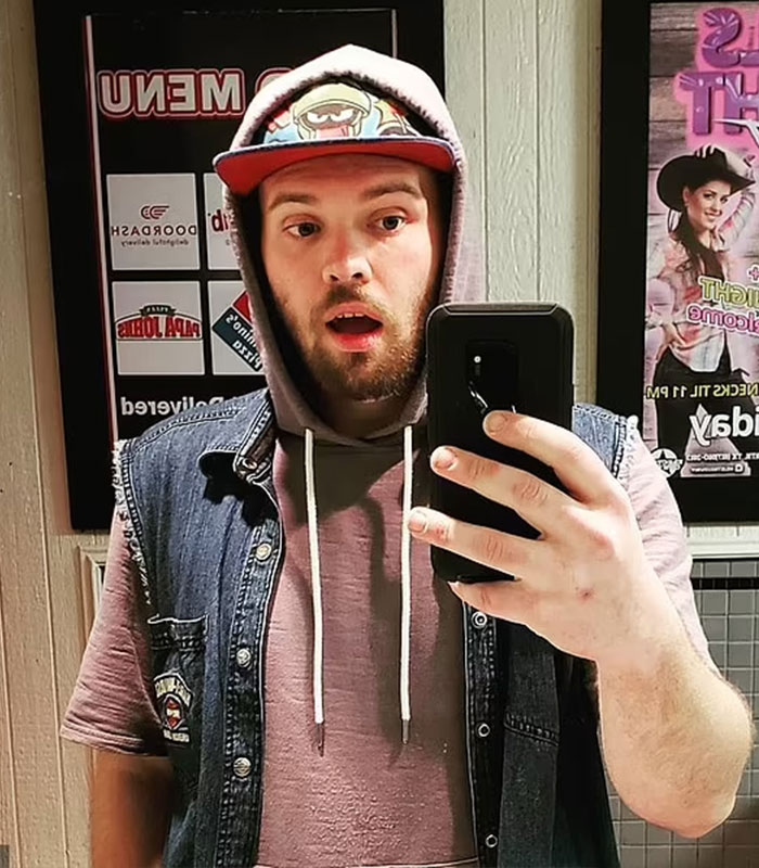 A FedEx driver in a denim vest and hoodie takes a selfie, capturing his surprised expression.