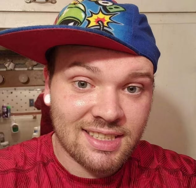 Smiling FedEx driver wearing a colorful cap and red shirt. Related to the Athena Strand case.