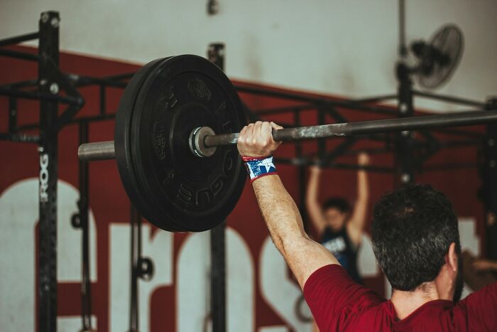 Man lifting heavy barbell in gym, illustrating random life decisions leading people to the right place through strength training.