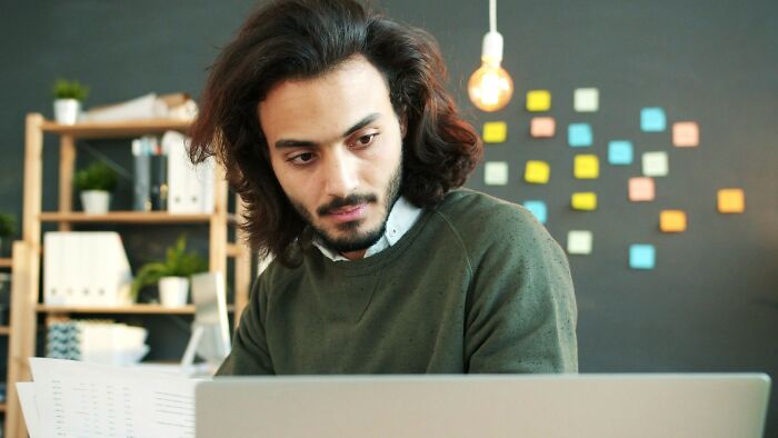 Man looking concerned at laptop screen, experiencing mortification after accidentally sending a message at work.
