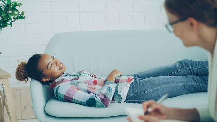 A woman lying on a couch during a therapy session with a counselor, highlighting jobs AI can’t touch.