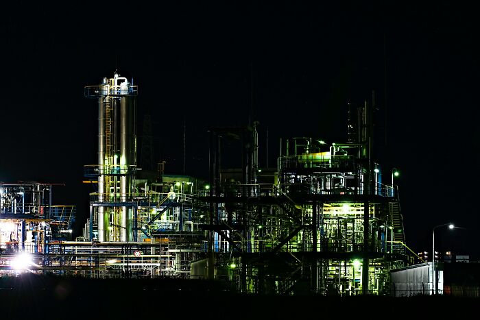 Industrial building complex at night with bright lights, illustrating jobs that AI cannot replace in construction and industry.