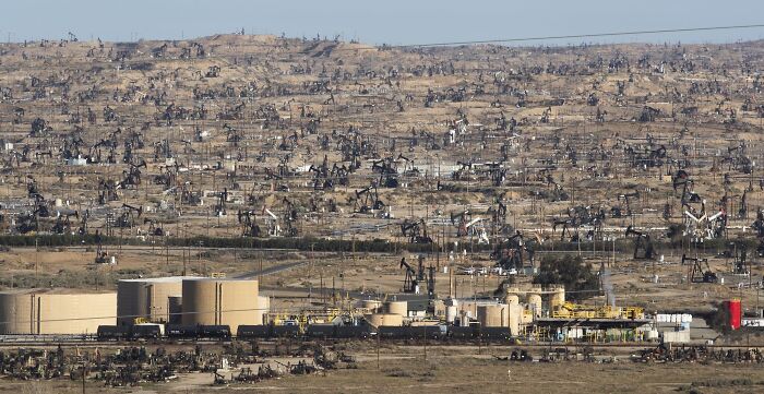 Vast oil field with pumpjacks stretching across dry land, an example of some worst places in the US to visit.