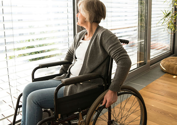 Older woman in a wheelchair looking out a window, illustrating concepts related to scientists' biggest unproven theories.