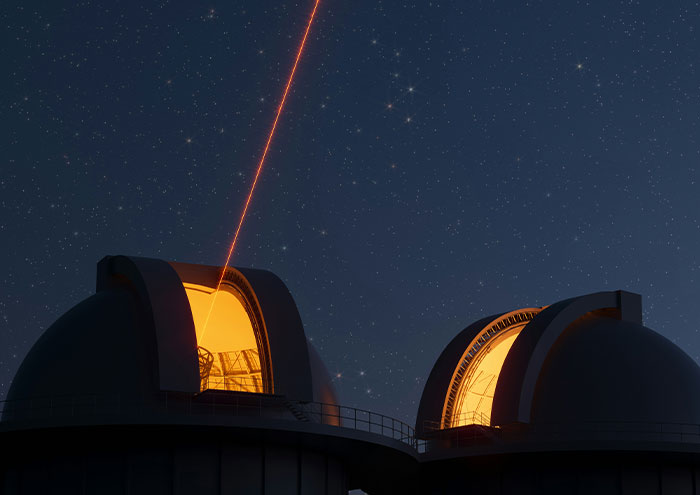 Observatory domes at night with a red laser beam pointing skyward, illustrating scientists biggest unproven theories.