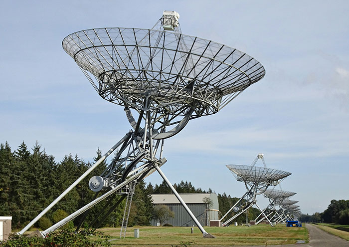 Large radio telescope antennas aligned outdoors, representing scientists exploring unproven theories in astrophysics research.