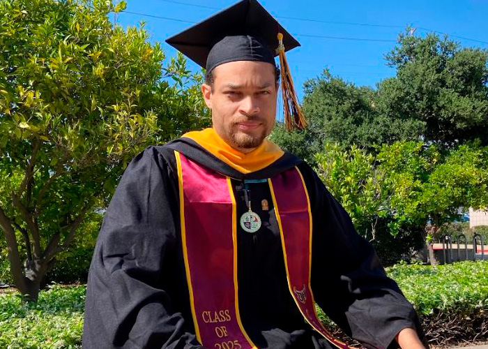 A man in graduation regalia, identified as a California teacher, looking directly at the camera with a serious expression.