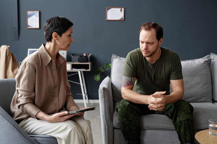 Couple in therapy session discussing marriage problems, man appearing troubled, capturing marriage twist and bedroom conflict.