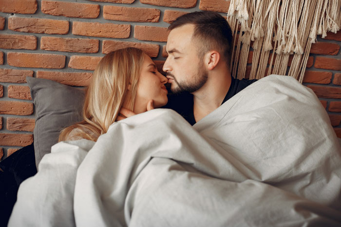 Couple cuddling under blanket in bedroom, illustrating marriage struggles and a surprising bedroom twist moment.