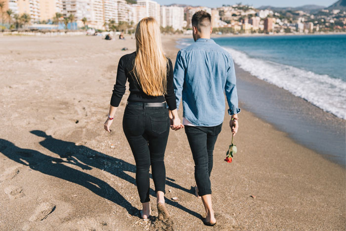 Couple walking hand in hand on the beach, highlighting tension over wife's obsession with low-class ex and marriage struggles.