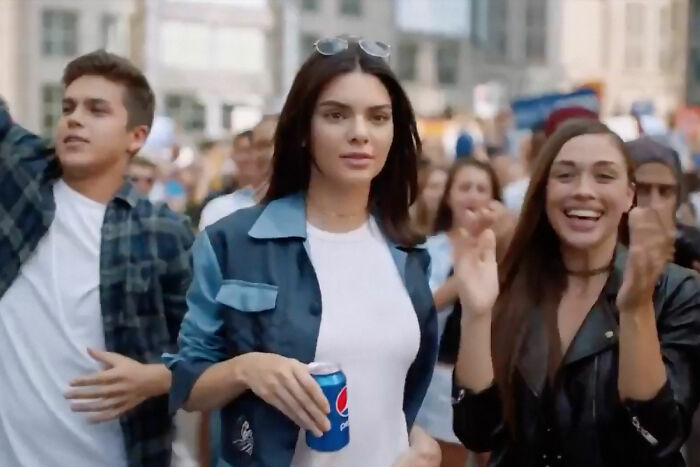 A young woman holding a can of soda at a crowded outdoor event, illustrating marketing fails with big budgets.