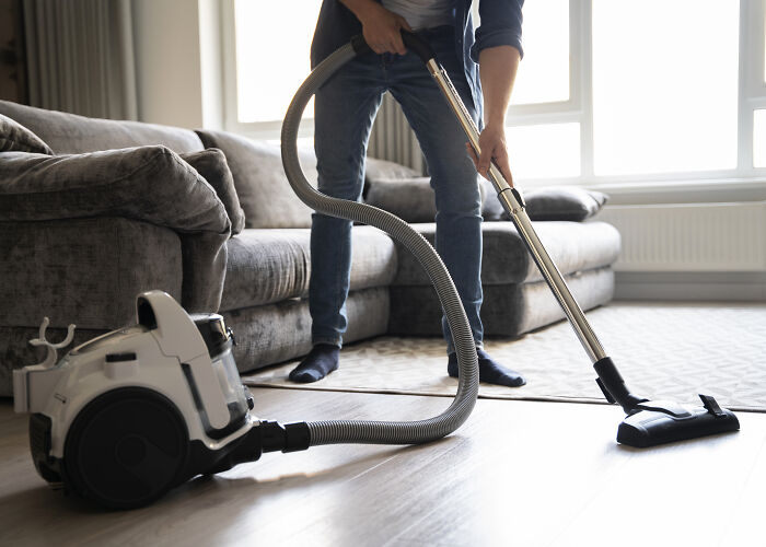 Person vacuuming a living room floor near a sofa, illustrating concepts of marketing fails and ineffective strategies.