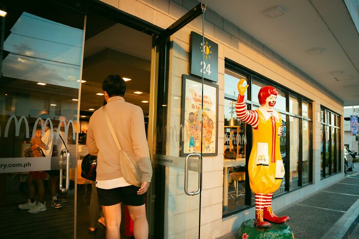 Person entering McDonald’s restaurant with Ronald McDonald statue outside, illustrating marketing fails with big budgets.