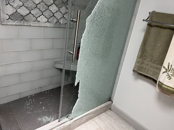 A broken glass shower door with shards on the floor, a home improvement fail.