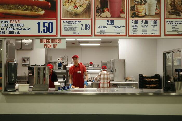 Fast food workers wearing red uniforms behind counter under menu, illustrating people who met former bullies in everyday life.