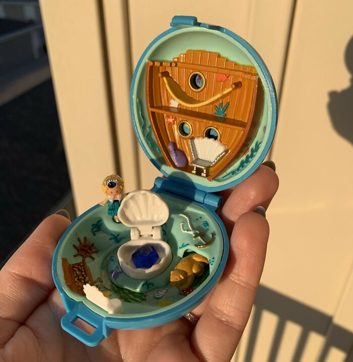 Polly Pocket compact in hand, featuring a mermaid, gem, and ship interior. A nostalgic toy reflecting on friendship betrayals.