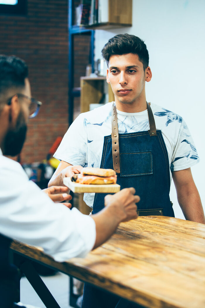 Restaurant staff serving a sandwich to a customer, highlighting rude customers who learned not to mess with staff.