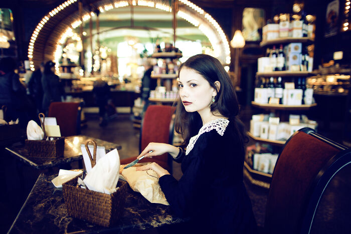 Woman sitting in a cafe looking dissatisfied while opening a paper bag, illustrating rude customers learning not to mess with staff.