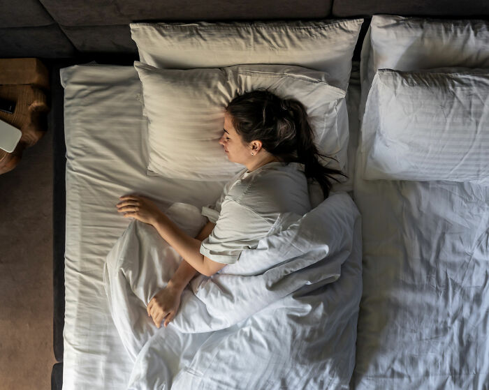 Woman lying in bed looking distressed, representing investigation into depraved website offering harmful advice to men.