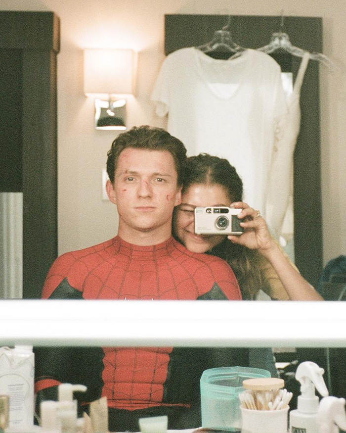 Zendaya taking a mirror selfie with co-star dressed as Spider-Man, showcasing the sheer dress trend during movie promo.